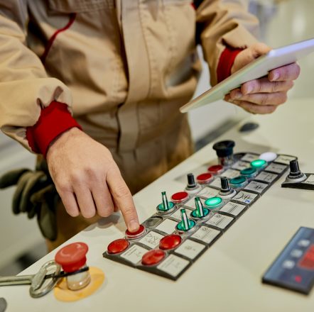 Close-up of a worker using automated machine at woodworking production facility.