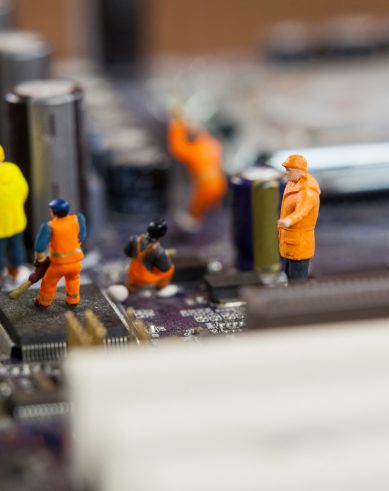 Conceptual image of miniature workers working on chip of motherboard